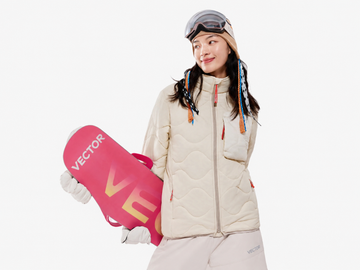 A snowboarder wearing a lightweight insulated mid layer and holding a snowboard, representing the versatility of insulated mid layers for skiing and outdoor adventures.